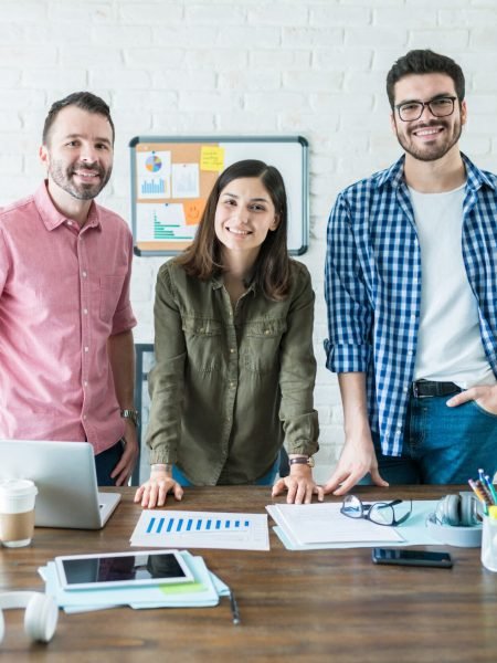 Portrait of confident professionals standing at conference table in meeting room at office